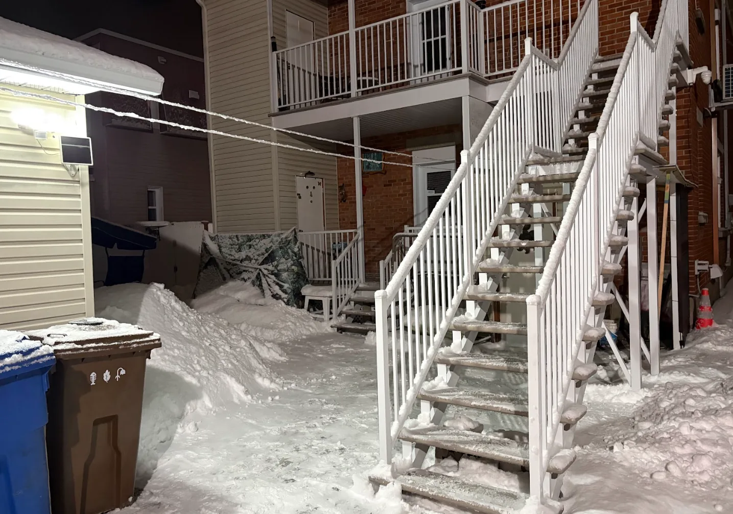 Escalier extérieur et accès d’un immeuble après une intervention de déneigement en soirée