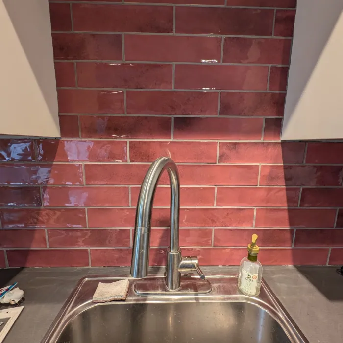 Dosseret décoratif rouge derrière un robinet de cuisine