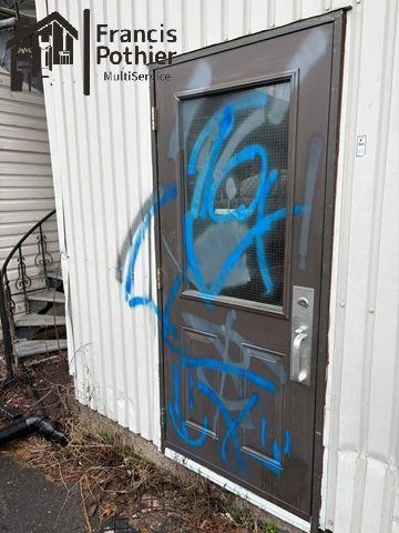Porte brune marquée de graffiti avant intervention à Shawinigan